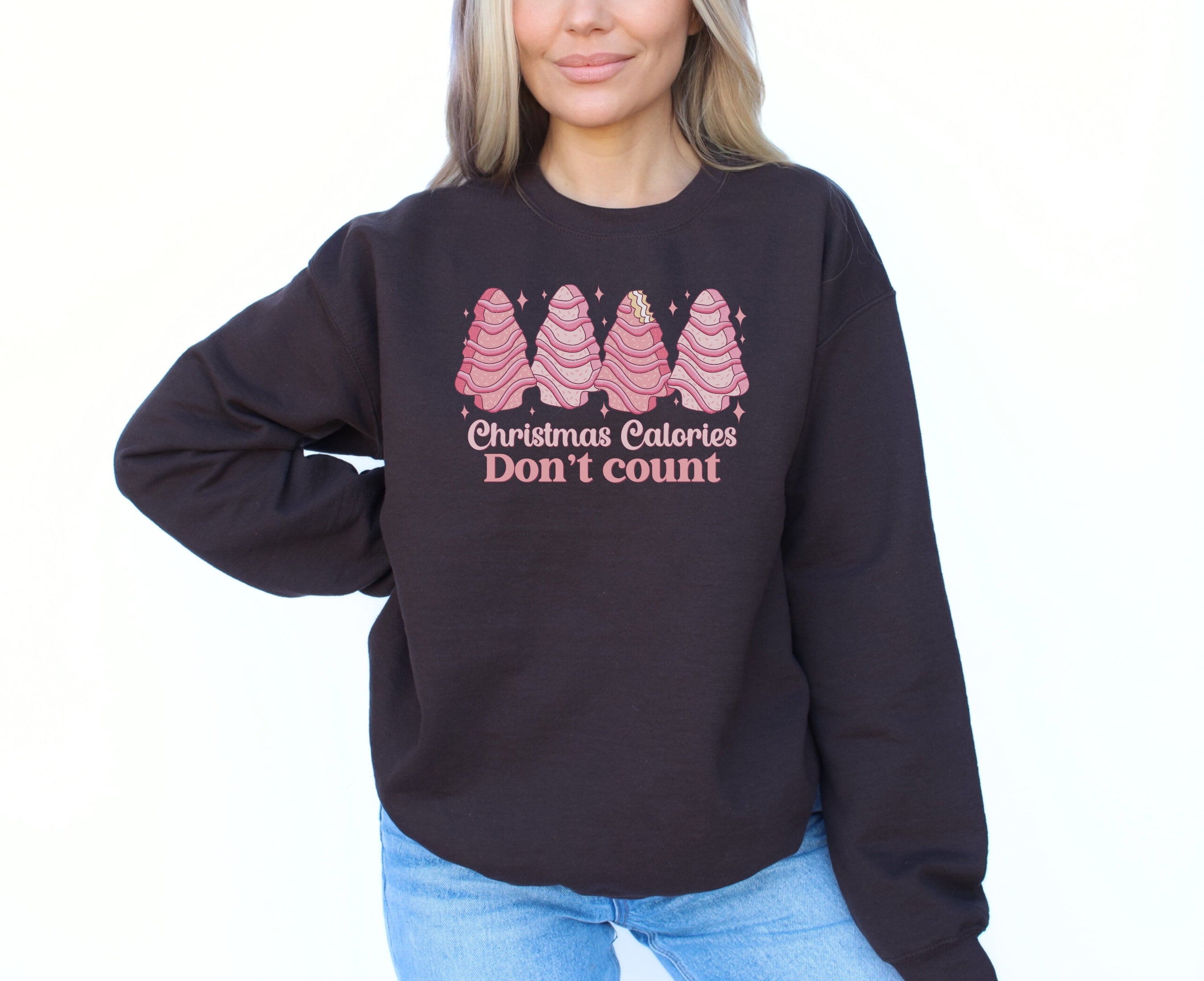 Girl wearing chocolate brown sweatshirt with pink Christmas tree cakes on it