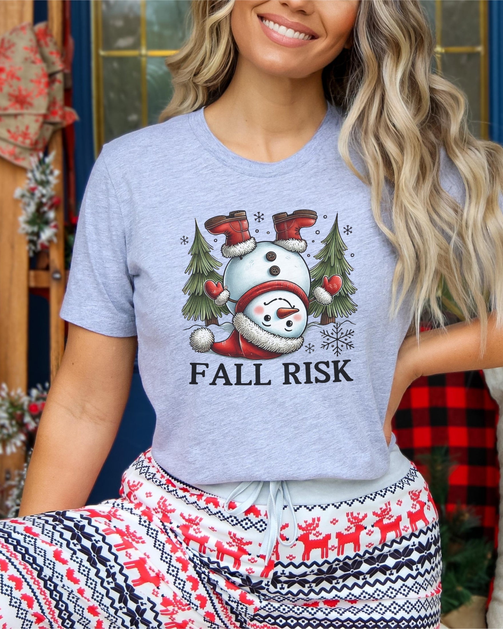 Girl wearing athletic heather t-shirt with snowman falling down saying fall risk