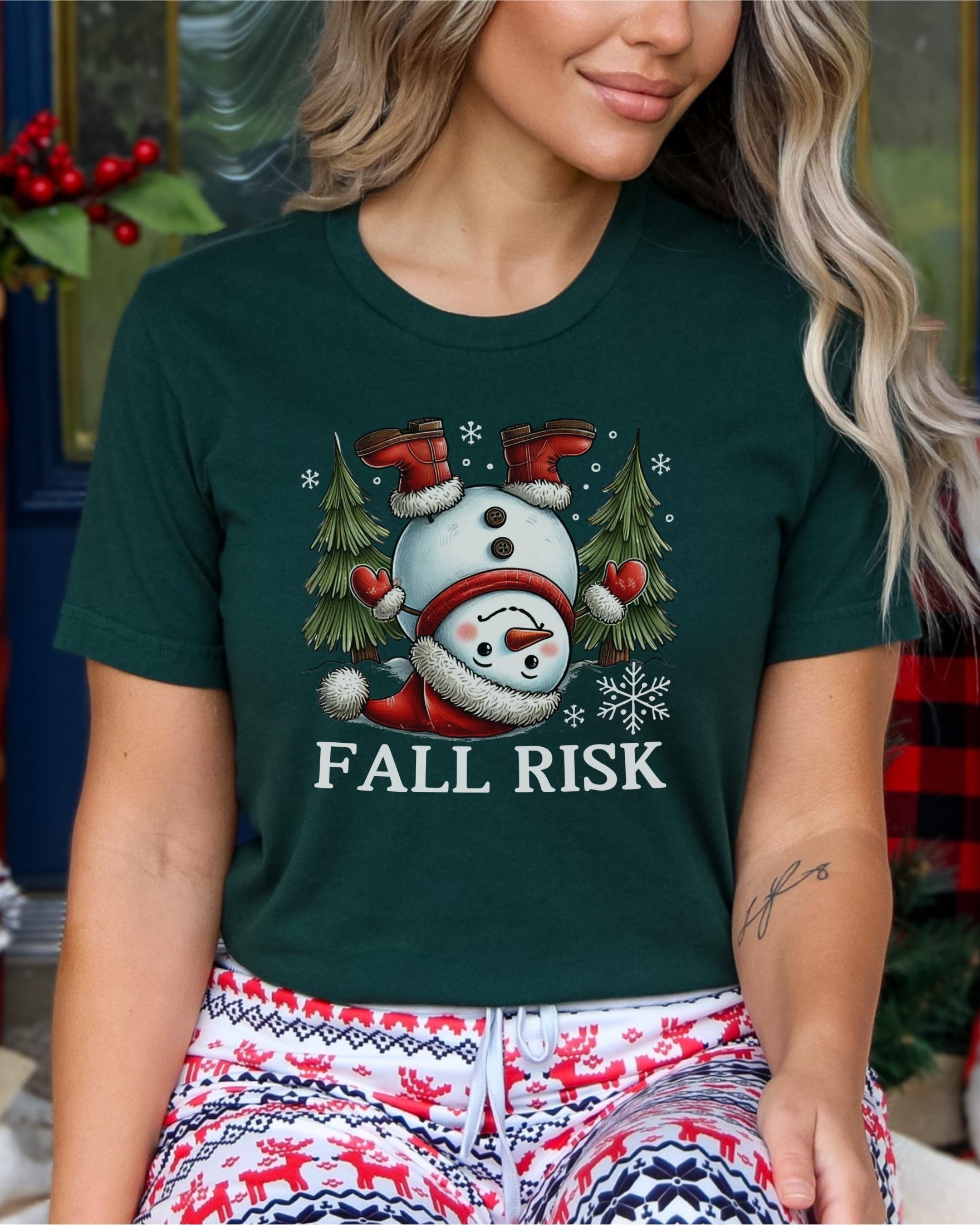 Woman wearing forest green t-shirt with snowman falling down saying fall risk
