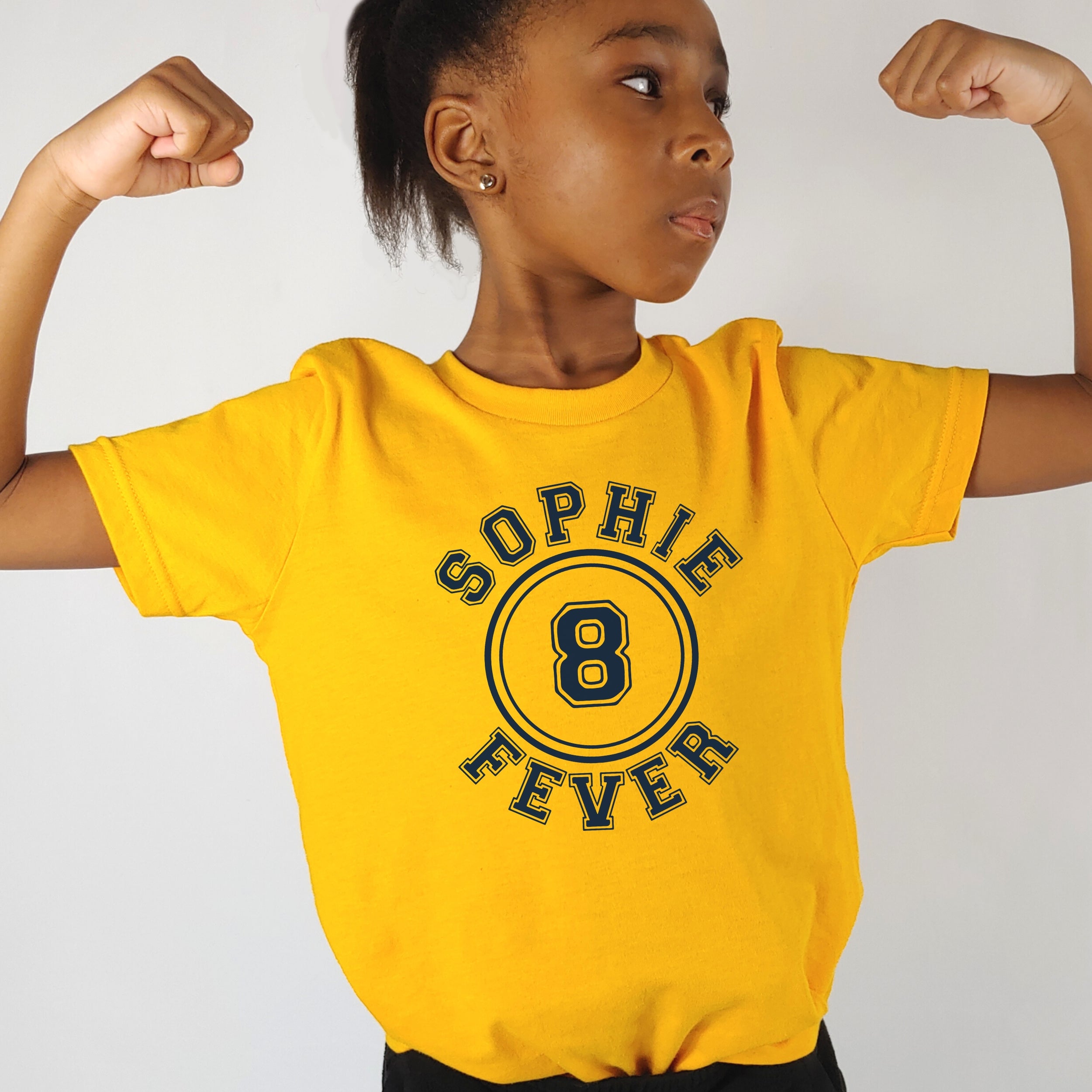 Child wearing a yellow t-shirt with 'Sophie Fever' printed on it, flexing muscles against a plain background