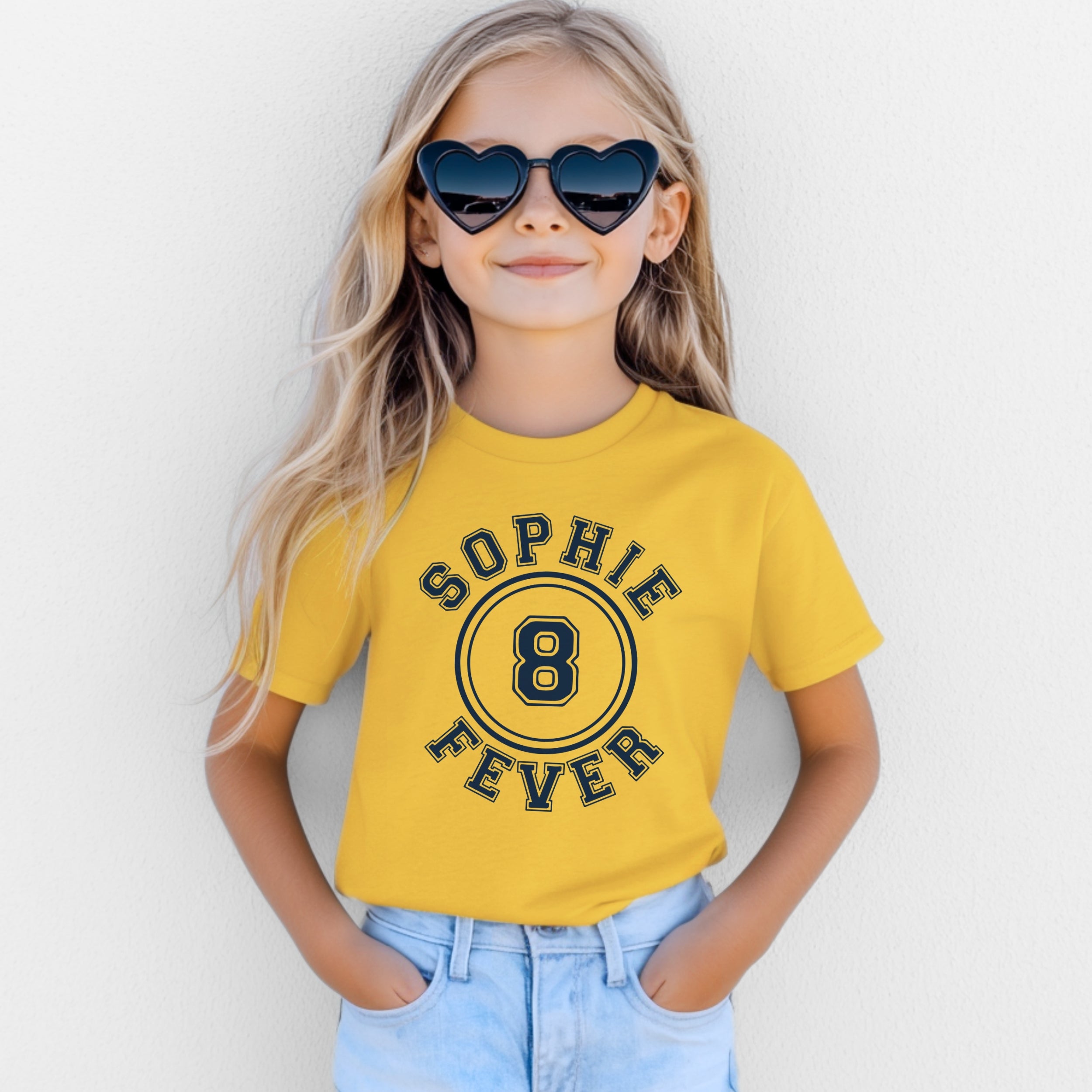 Child wearing a yellow t-shirt with 'Sophie 8 Fever' text, sunglasses, and blue jeans against a white background