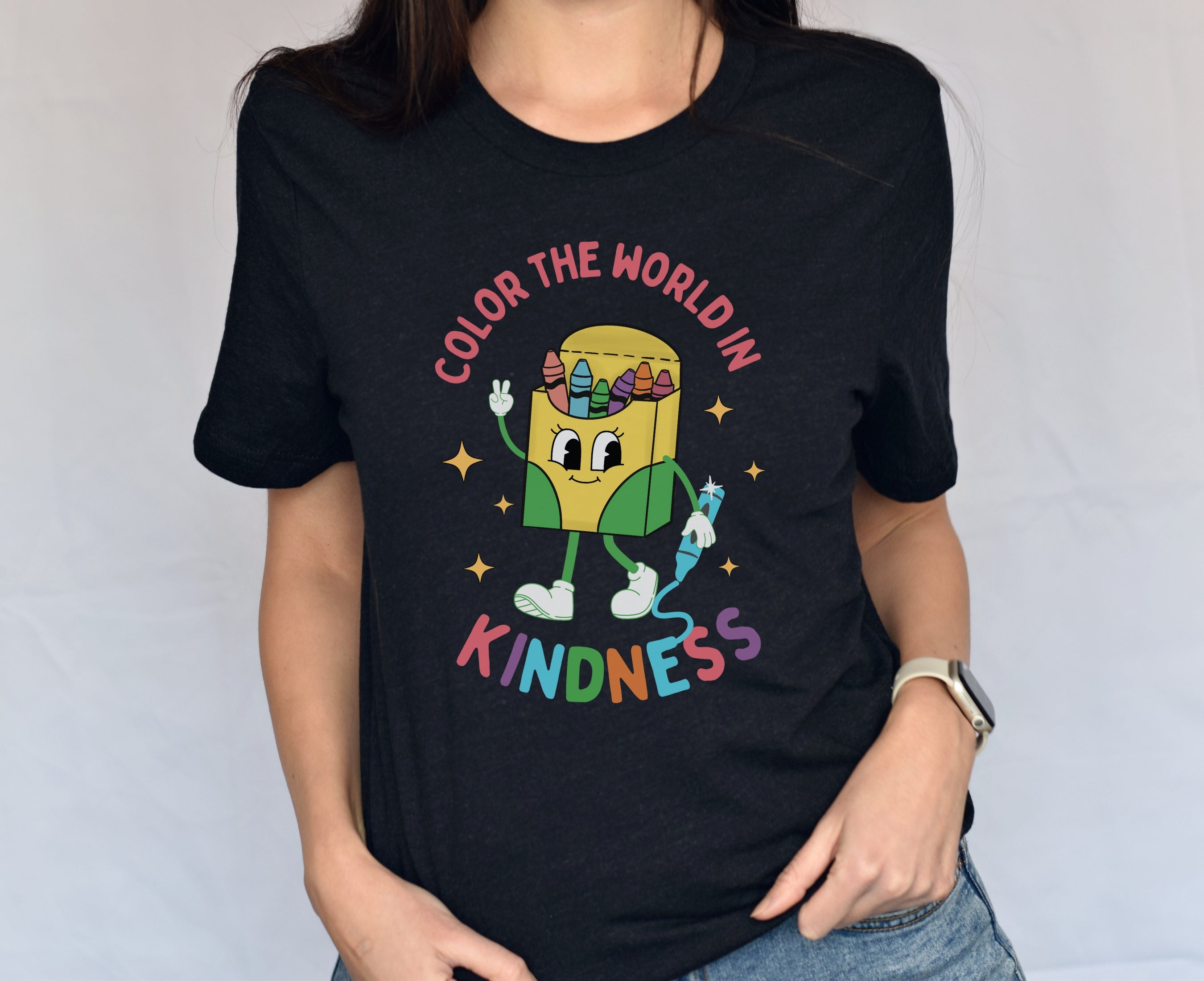 Woman wearing black be kind shirt featuring cute crayon box character