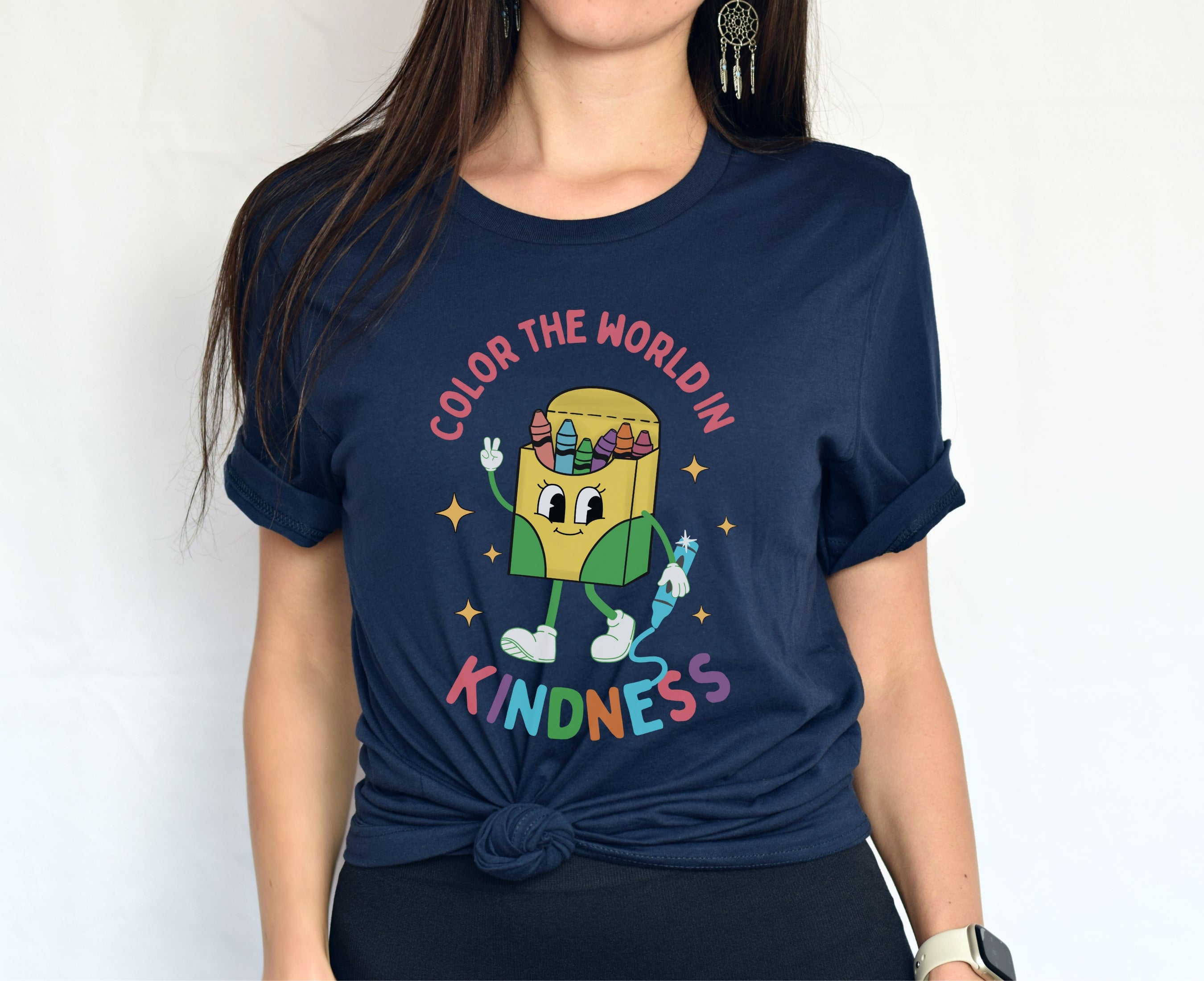 Elementary teacher wearing navy color the world in kindness shirt