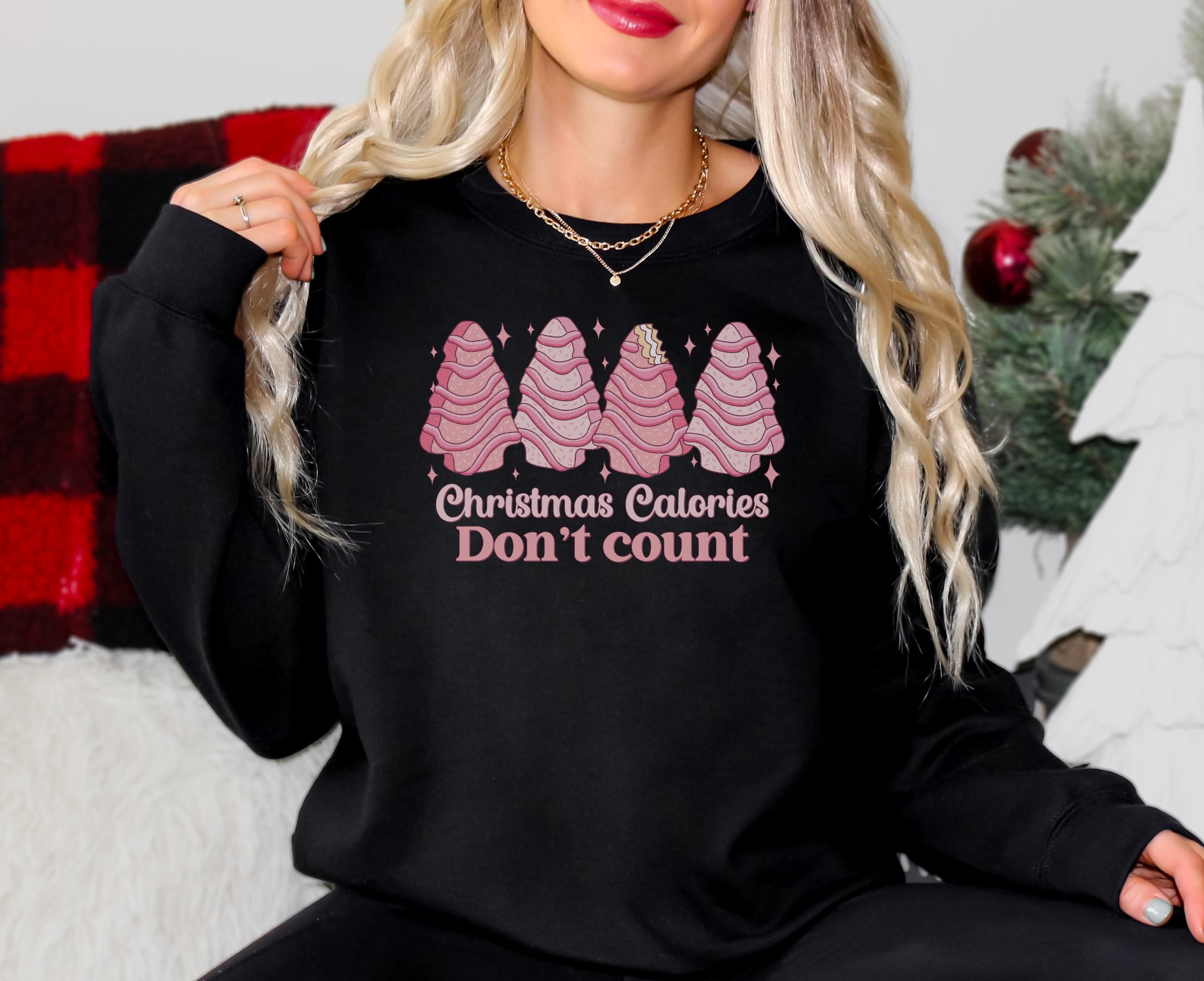 Girl wearing black sweatshirt with pink Christmas tree cakes on it