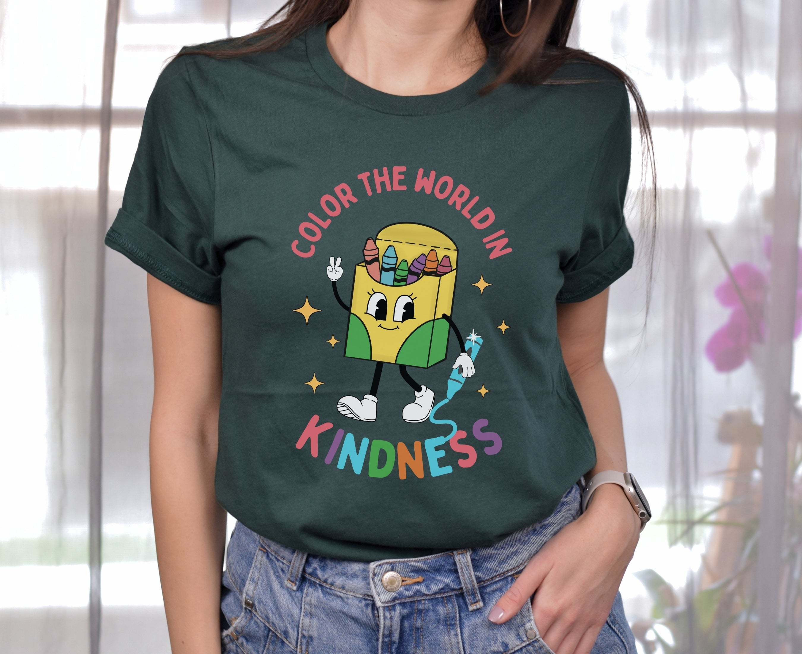 Teacher wearing forest green color the world in kindness shirt