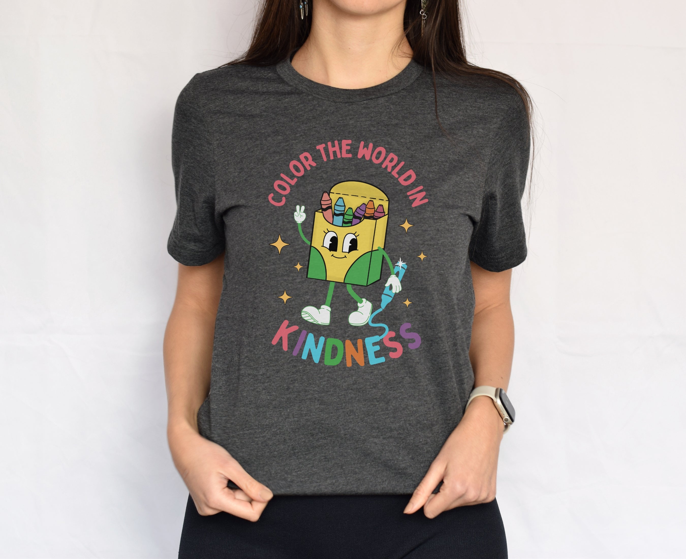 Woman wearing dark grey heather retro crayon box character be kind shirt