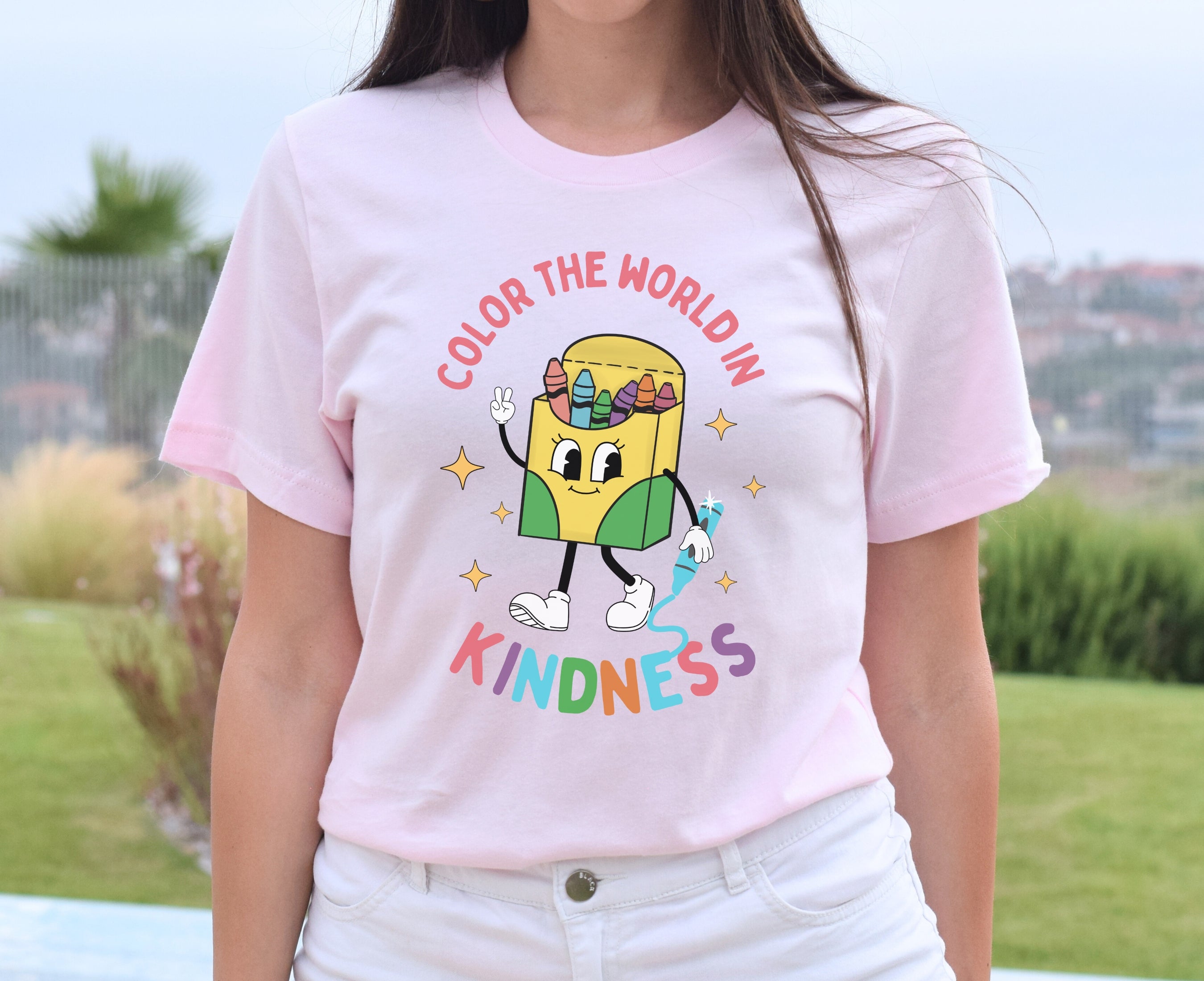 Girl wearing soft pink color the world in kindness shirt