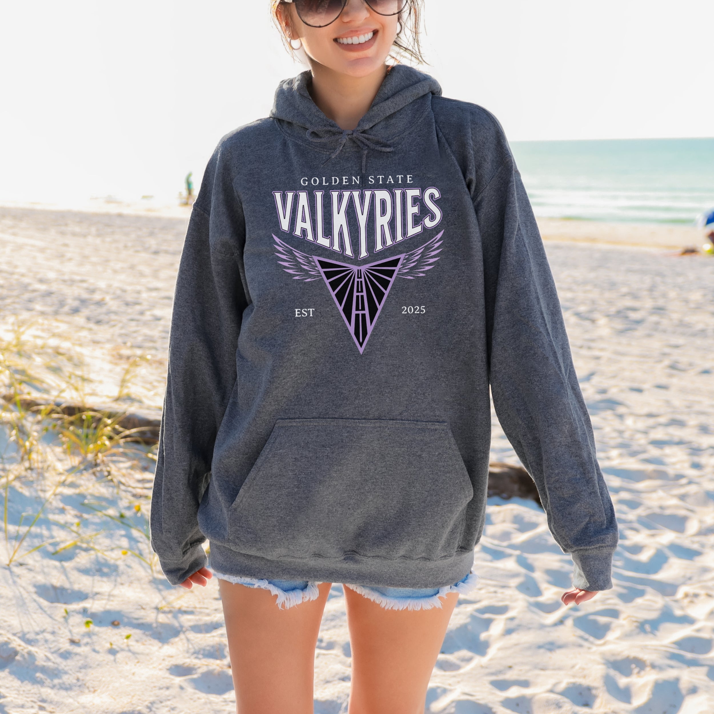 Person wearing a gray hoodie with 'Golden State Valkyries' on a beach