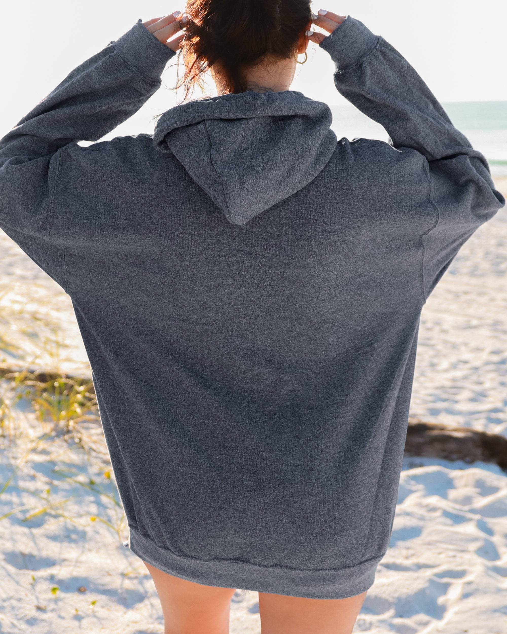 Person wearing a gray hoodie on a beach