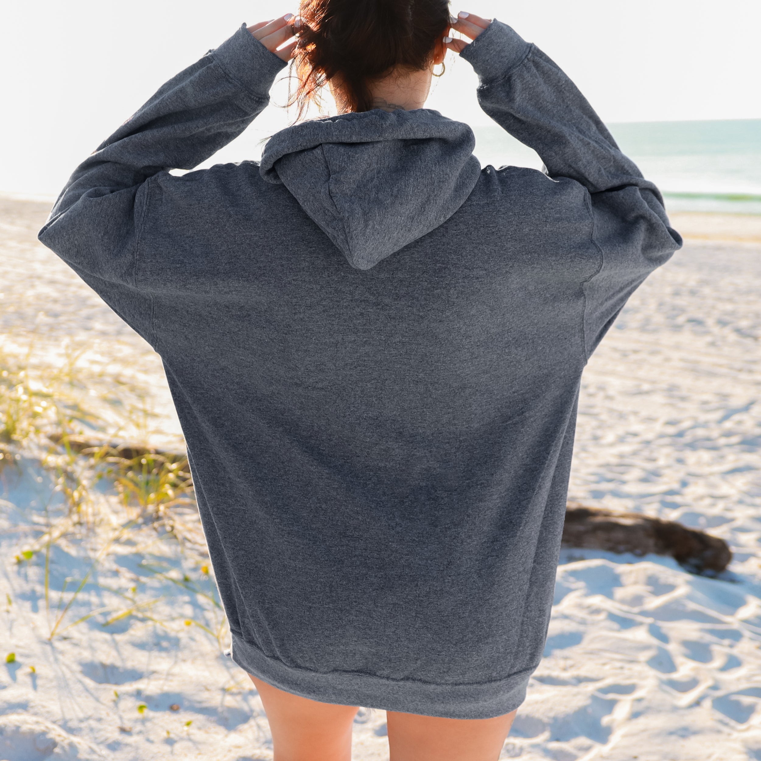 Person wearing a gray hoodie on a beach
