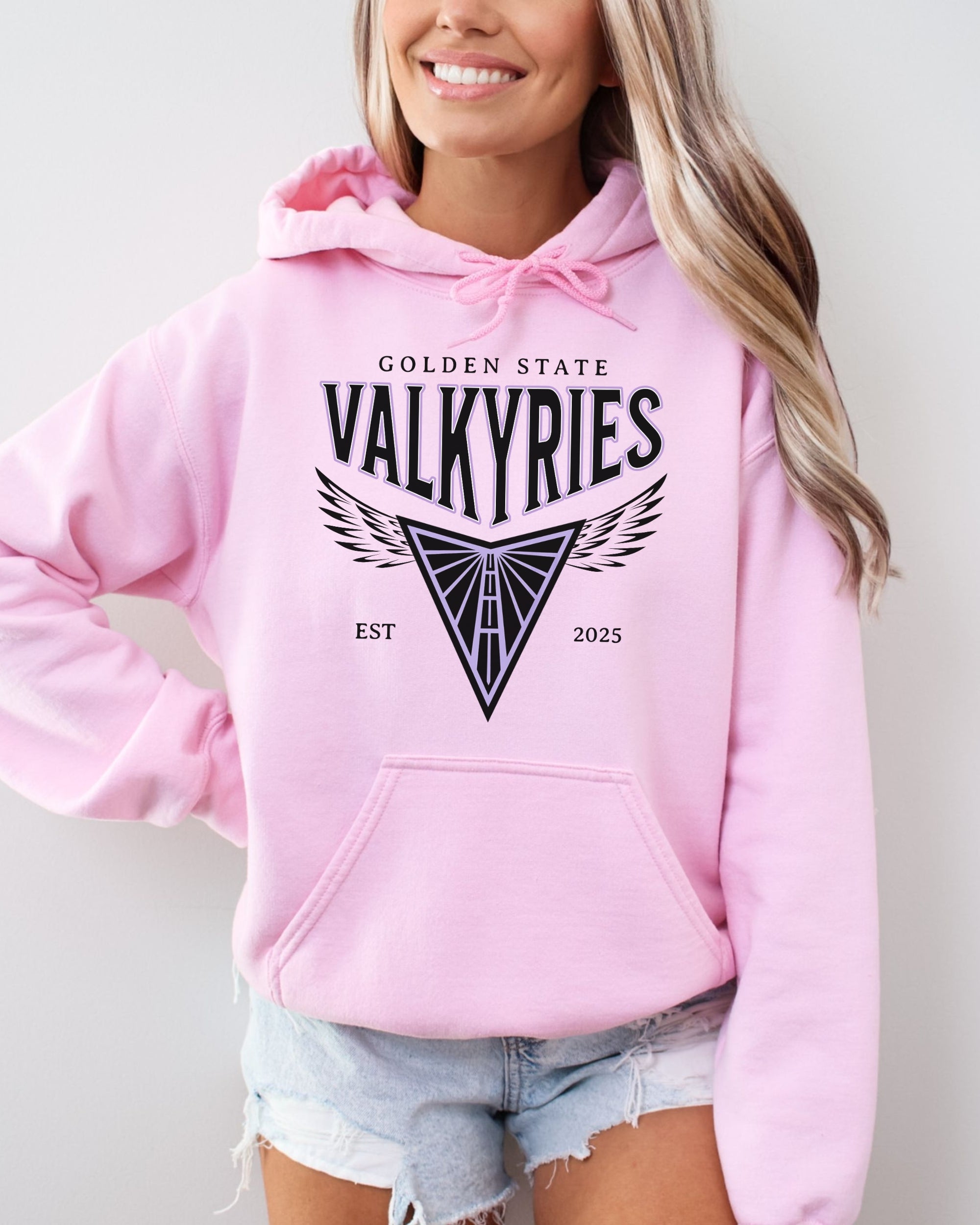 Person wearing a pink hoodie with 'Golden State Valkyries' design on a plain background