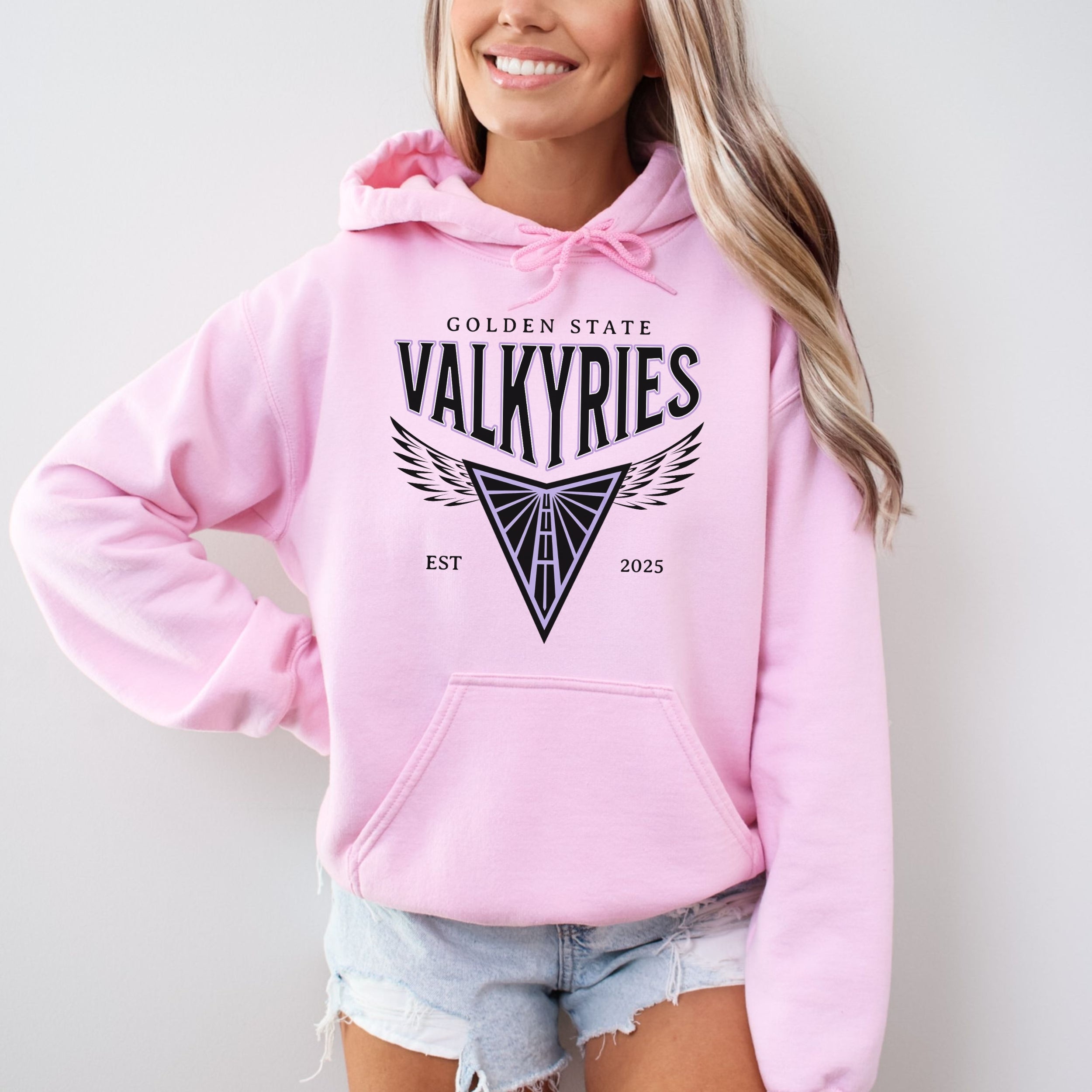 Person wearing a pink hoodie with 'Golden State Valkyries' design on a plain background