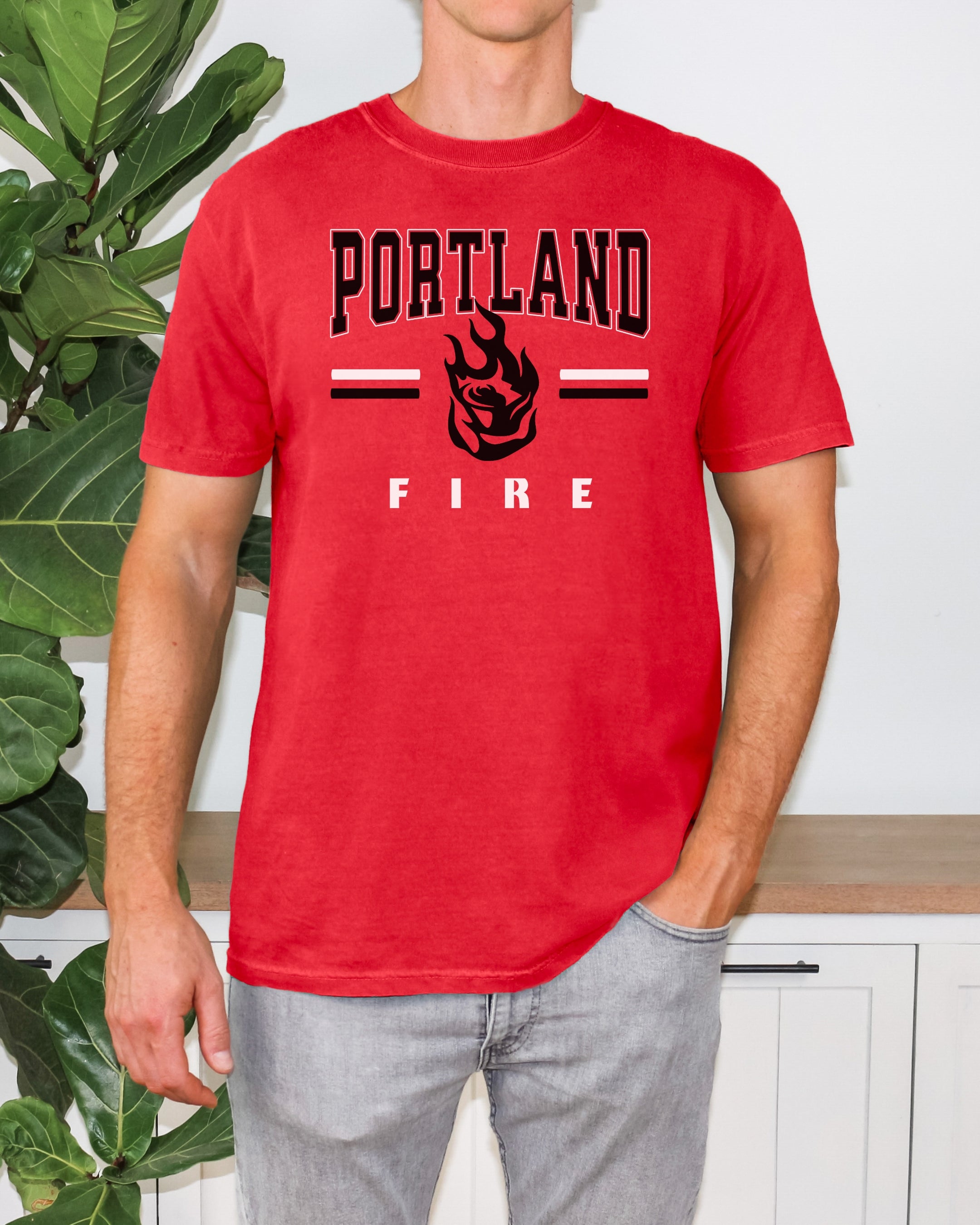 Person wearing a red t-shirt with 'Portland Fire' text and graphic, standing in front of a plant.