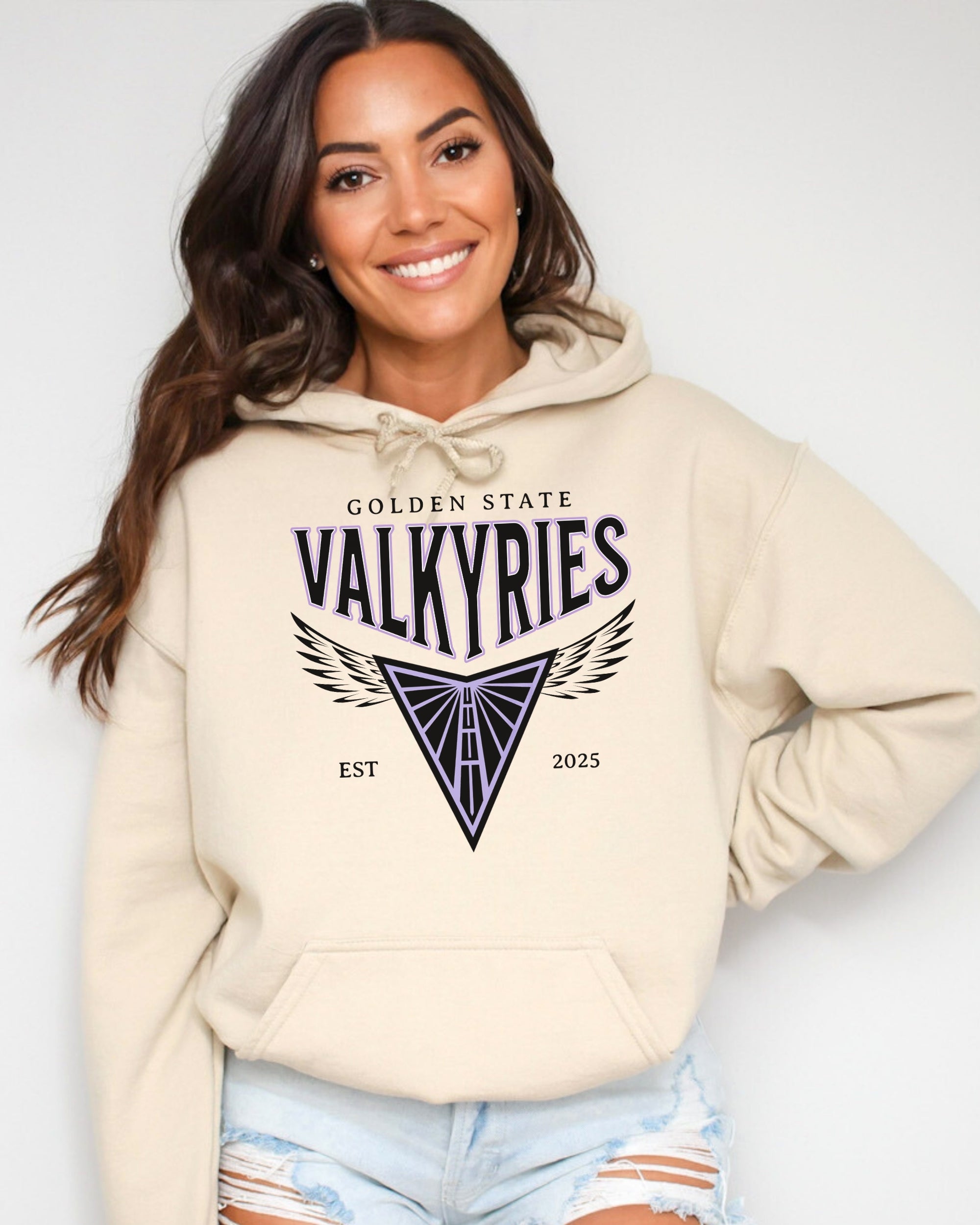 Woman wearing a beige hoodie with 'Golden State Valkyries' text and design on a plain background