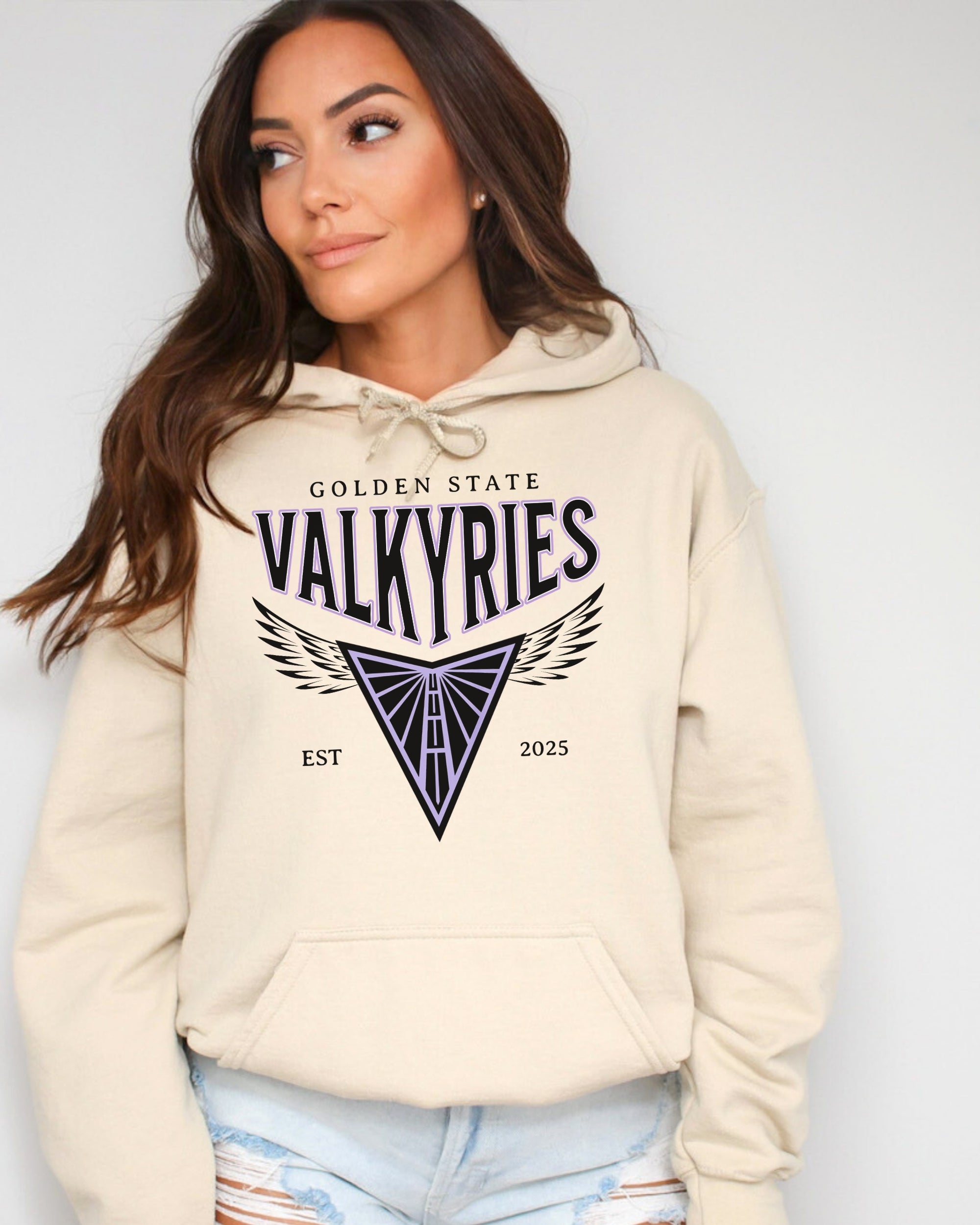 Woman wearing a beige hoodie with 'Golden State Valkyries' design on a plain background