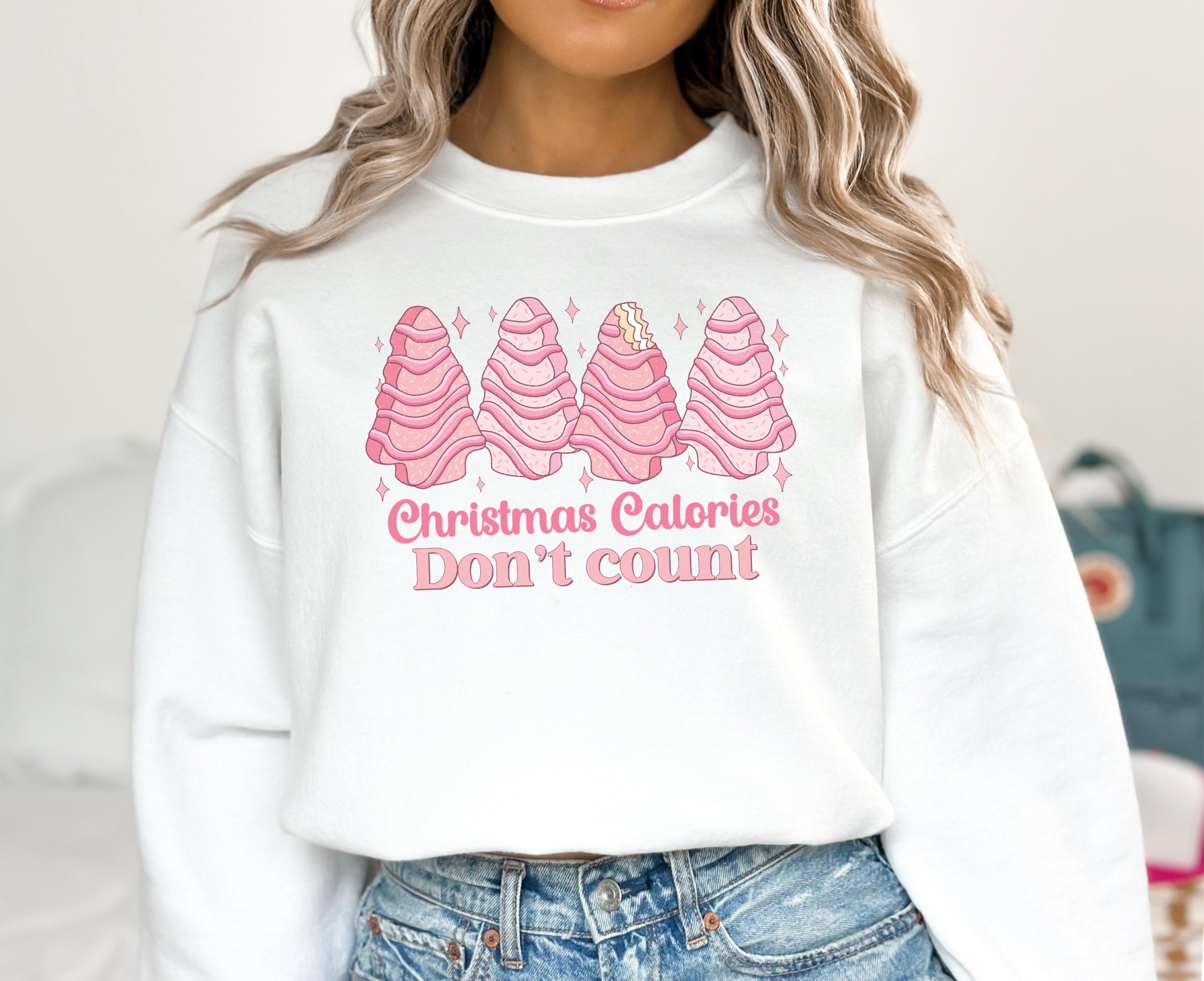 Girl wearing white sweatshirt with pink Christmas tree cakes on it