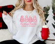 Girl wearing white sweatshirt with pink Christmas tree cakes on it