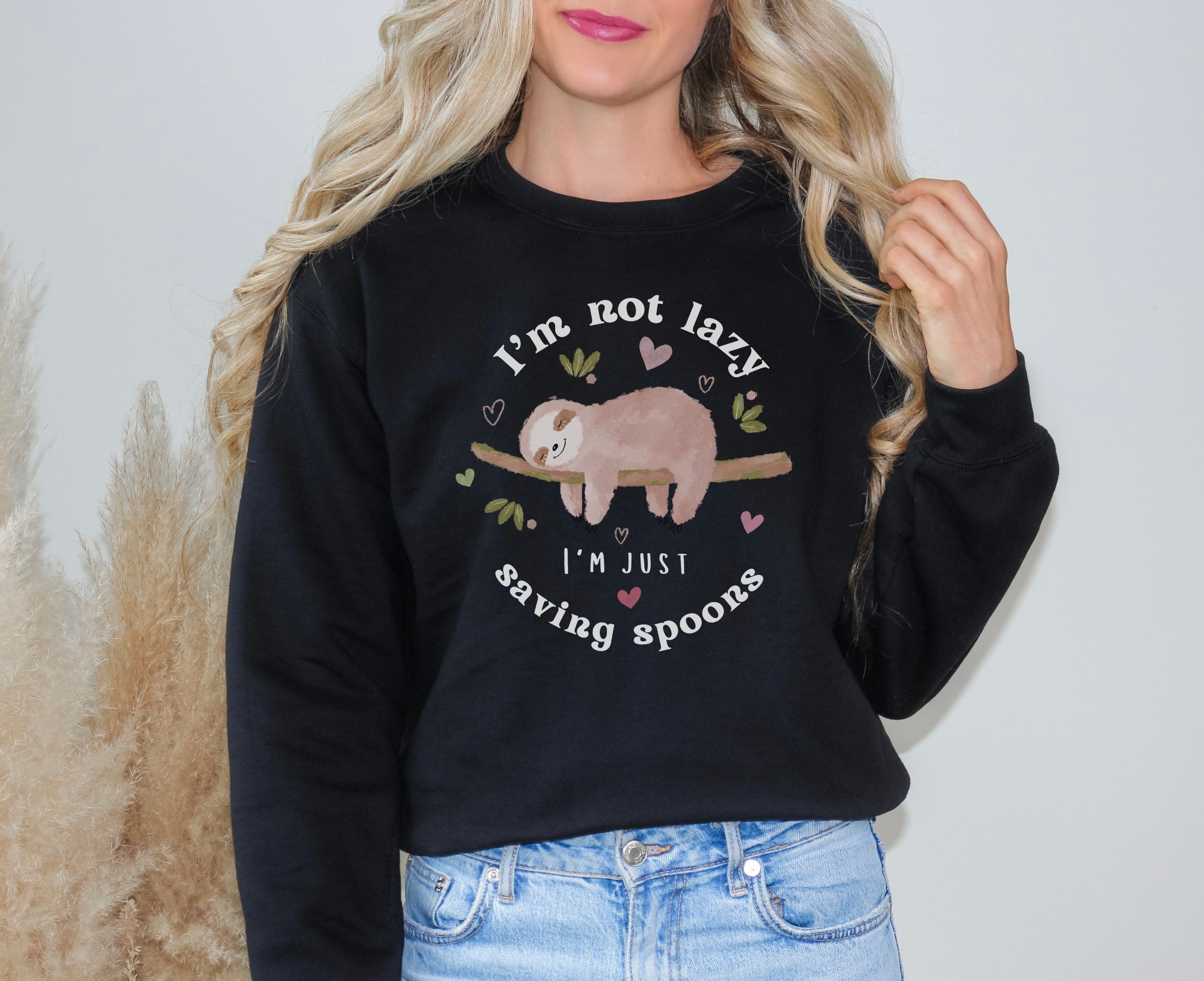 Woman wearing black sweatshirt with sleeping sloth on it