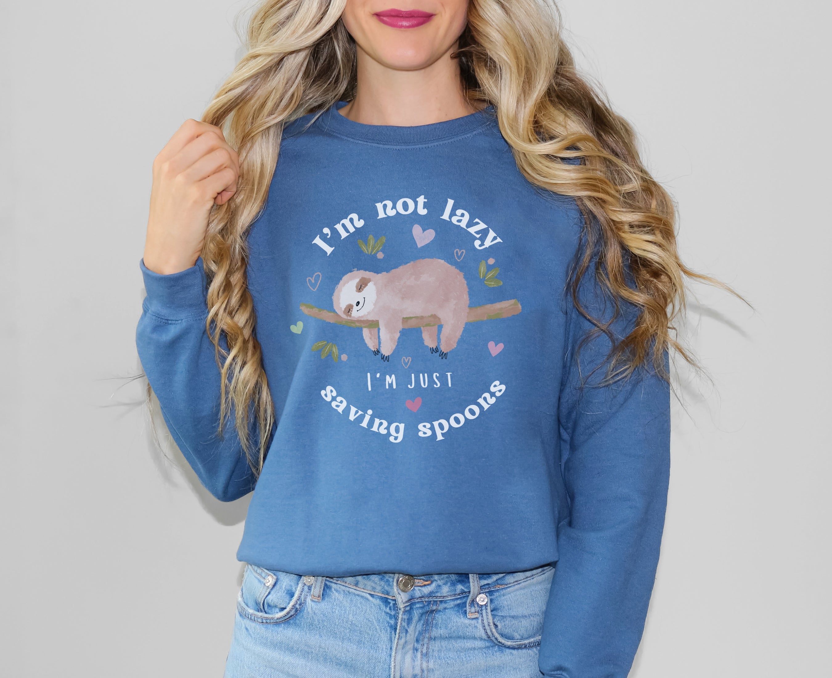Woman wearing indigo blue sweatshirt with sleeping sloth on it