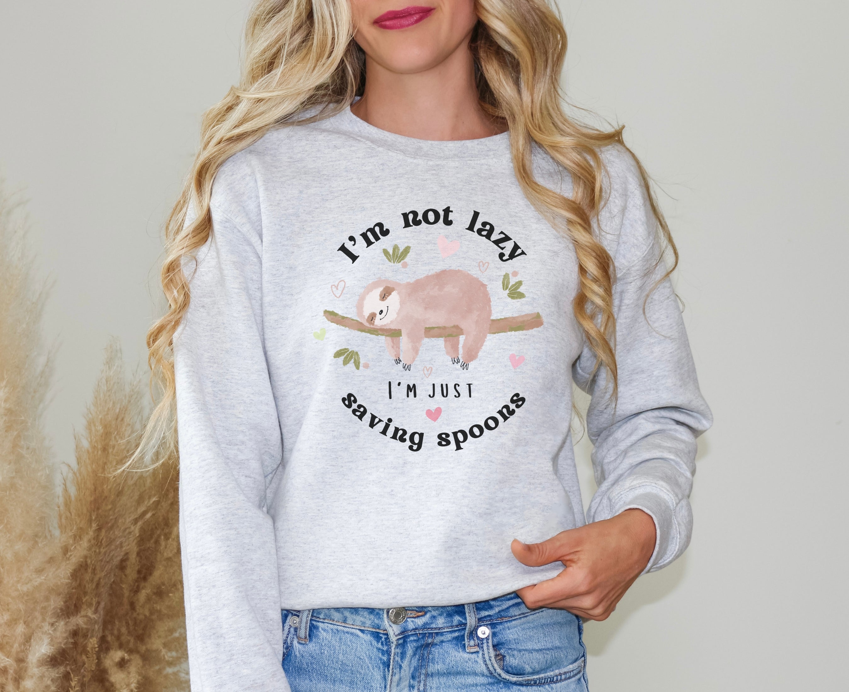 Woman wearing ash sweatshirt with sleeping sloth on it