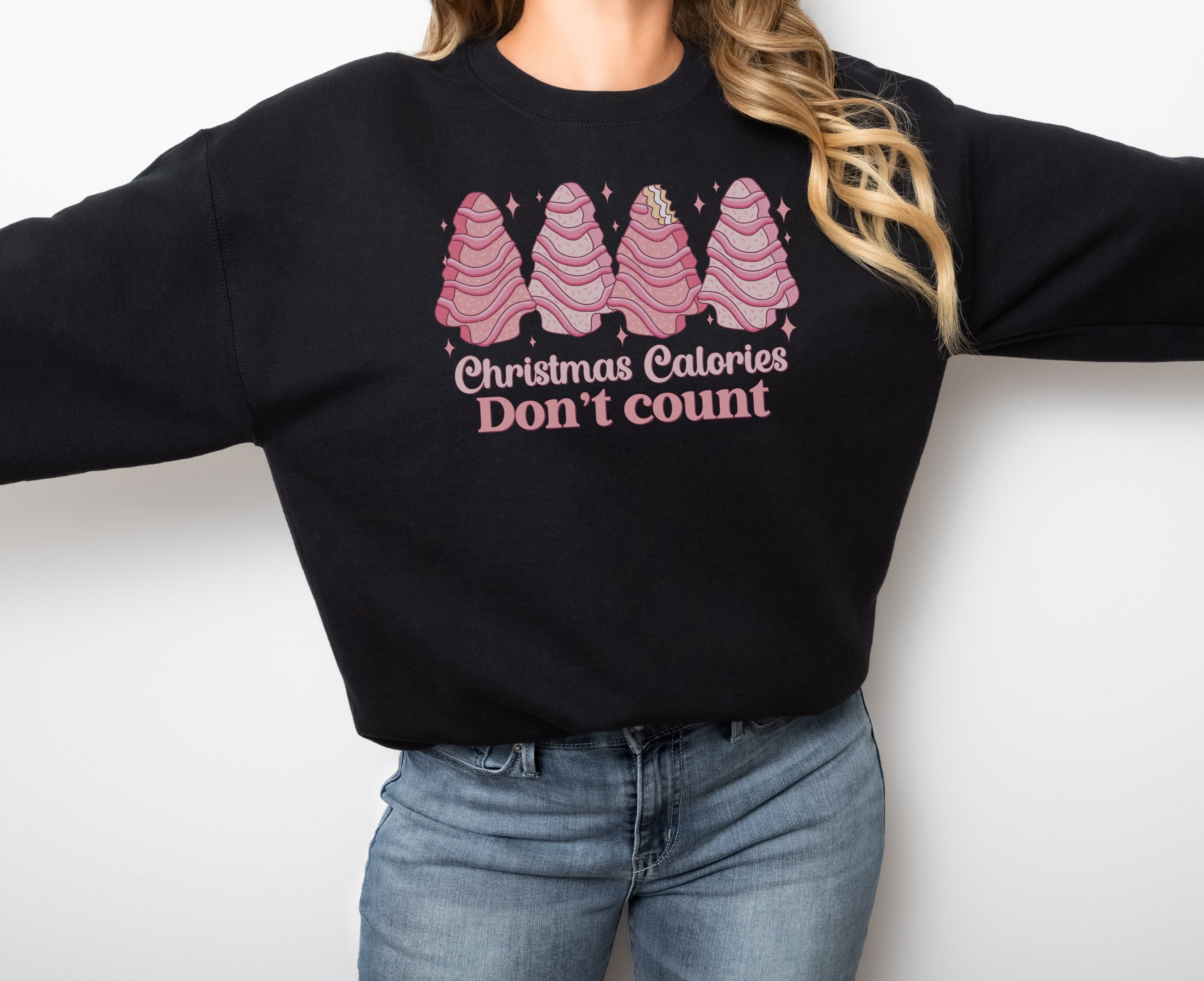 Girl wearing black sweatshirt with pink Christmas tree cakes on it