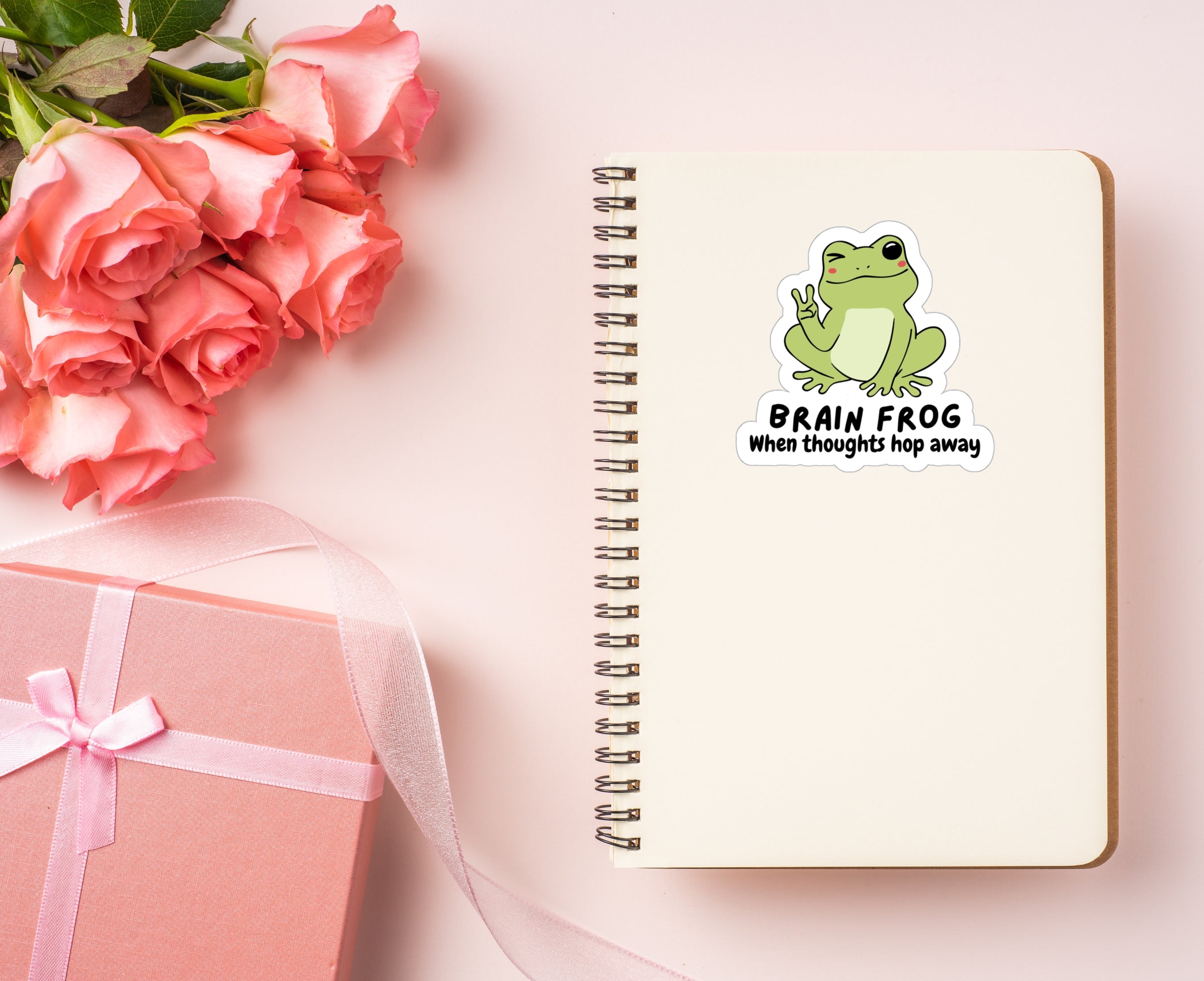 Sticker of a frog giving the peace sign on a notebook