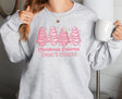 Woman wearing ash sweatshirt with pink Christmas tree cakes on it