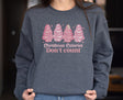 Girl wearing dark grey heather sweatshirt with pink Christmas tree cakes on it