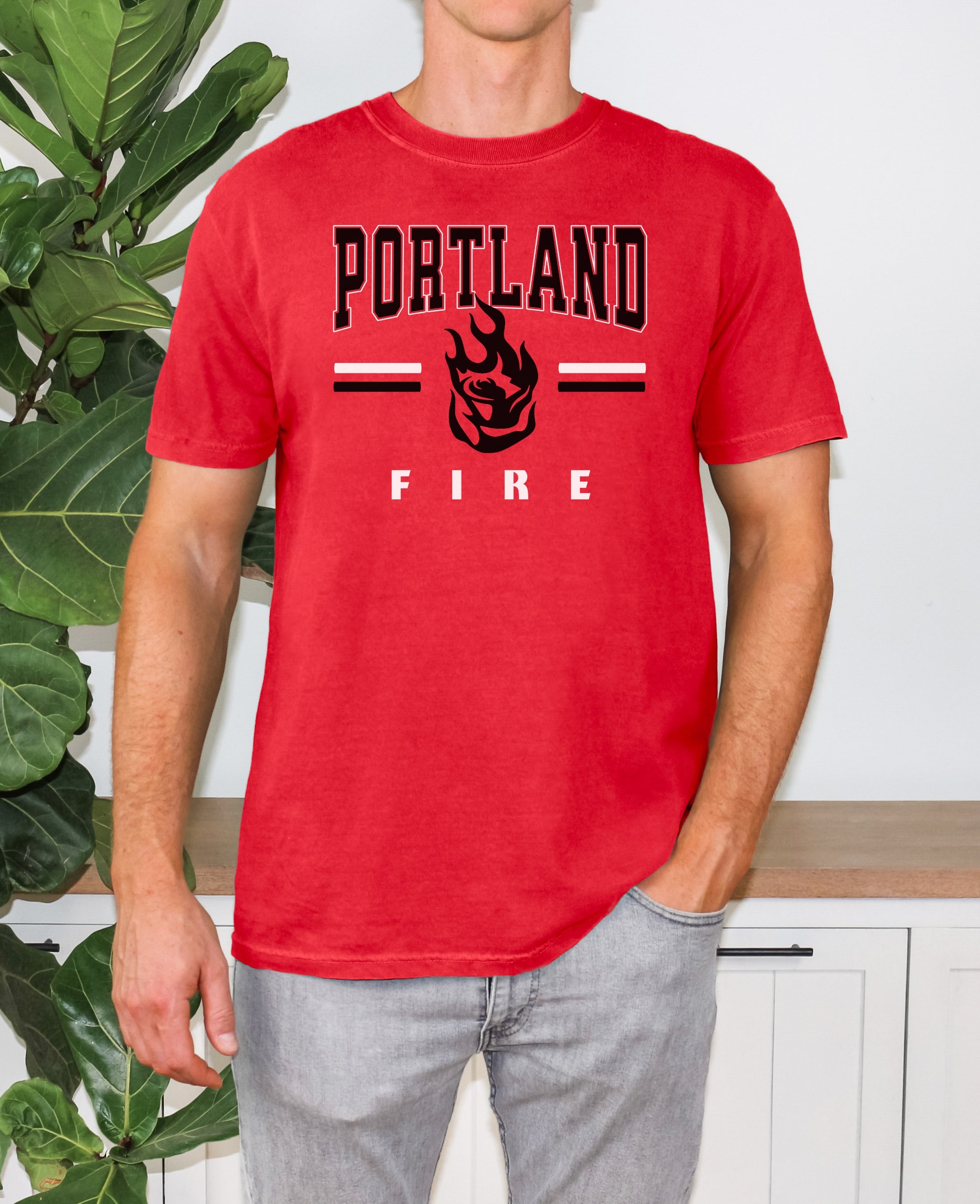 Person wearing a red t-shirt with 'Portland Fire' text and graphic, standing in front of a plant.