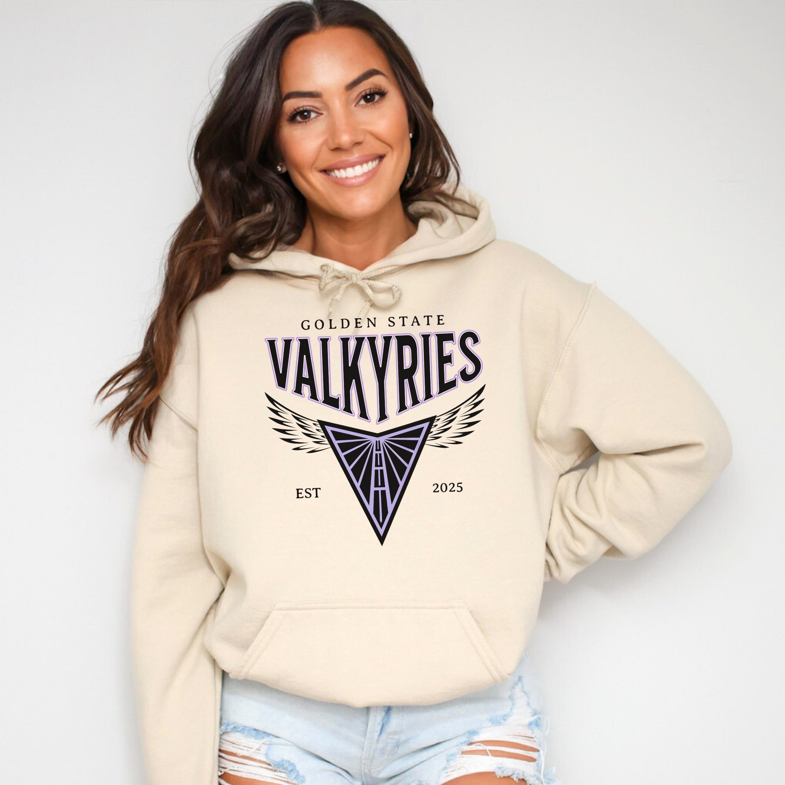 Woman wearing a beige hoodie with 'Golden State Valkyries' text and design on a plain background